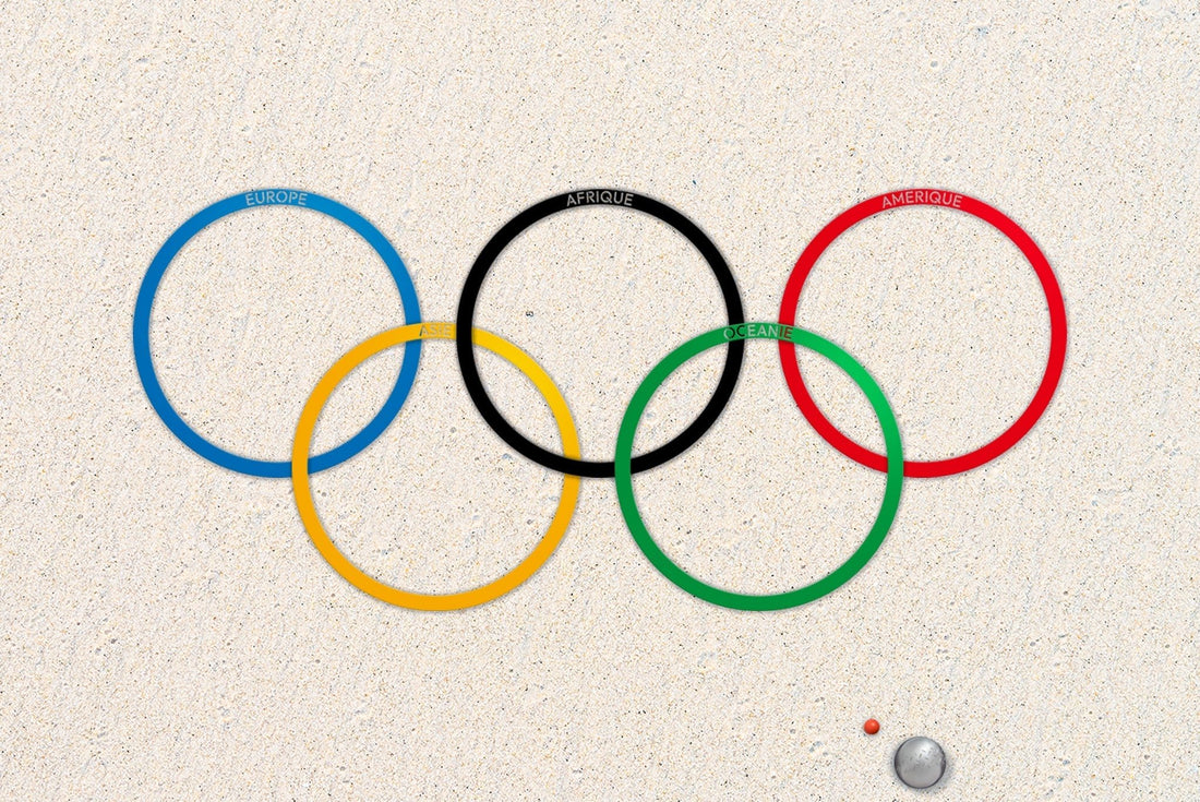 Cercles de pétanque en inox, disposés sur du sable blanc, formant le logo des Jeux Olympiques, avec les couleurs des cinq continents.